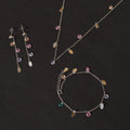 Silver-tone necklace and drop earrings with multicolor charm pendants, including purple and teal.